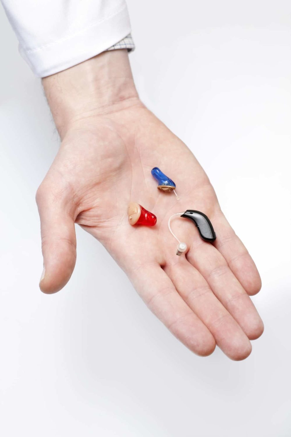Hand holding different hearing aid types including BTE and In the canal