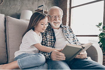 Man with hearing aids reading to his granddaughter. Serving MO, AR, and OK.